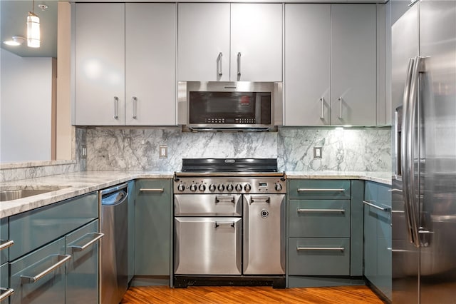 kitchen featuring backsplash, stainless steel appliances, light stone countertops, and light wood-type flooring