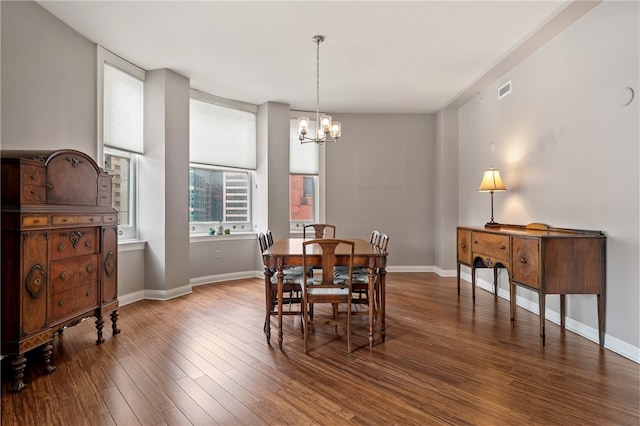 dining space with dark wood-type flooring and a notable chandelier