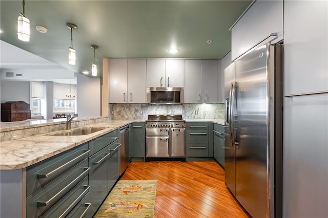 kitchen featuring gray cabinetry, hanging light fixtures, light hardwood / wood-style floors, sink, and stainless steel appliances