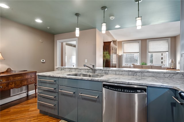 kitchen featuring light stone counters, decorative light fixtures, dishwasher, sink, and hardwood / wood-style flooring