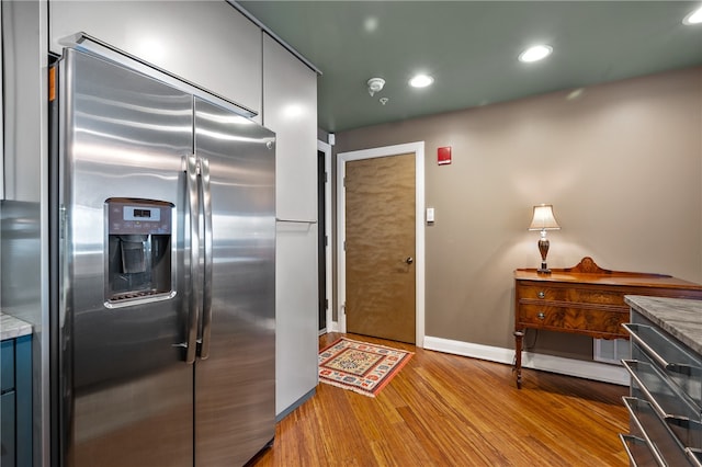 kitchen featuring high end refrigerator, stone countertops, and light wood-type flooring