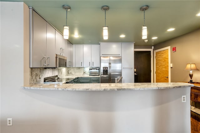 kitchen featuring kitchen peninsula, light stone counters, appliances with stainless steel finishes, backsplash, and decorative light fixtures