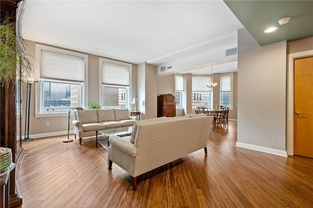 living room featuring a healthy amount of sunlight, a notable chandelier, and hardwood / wood-style flooring