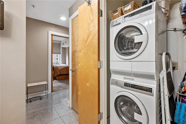 laundry room featuring light tile floors and stacked washer / drying machine