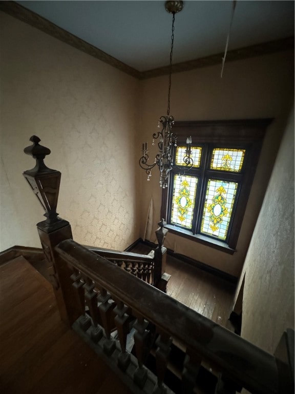 stairway featuring ornamental molding, a notable chandelier, and hardwood / wood-style flooring