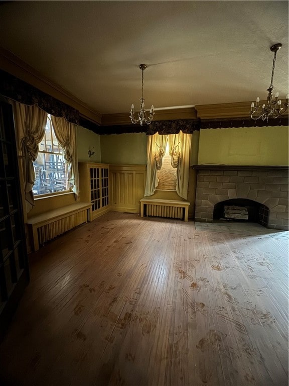 unfurnished dining area featuring a chandelier, a brick fireplace, hardwood / wood-style floors, and radiator heating unit