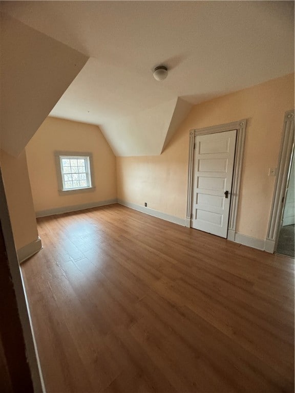 bonus room with vaulted ceiling and light hardwood / wood-style flooring