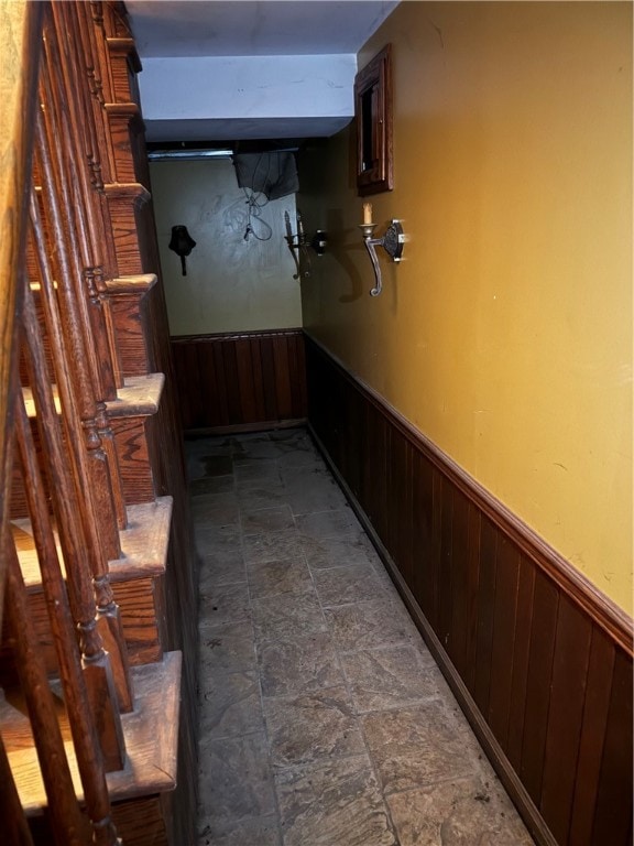 corridor featuring wood walls and dark tile floors