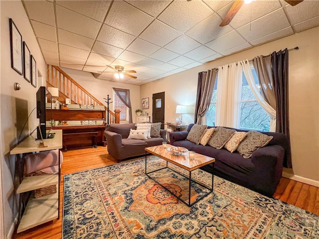 living room with hardwood / wood-style floors, ceiling fan, and a paneled ceiling