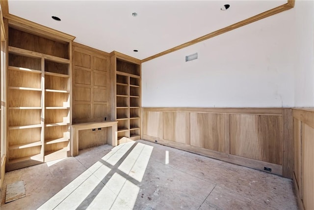 spare room featuring built in features, crown molding, and wooden walls