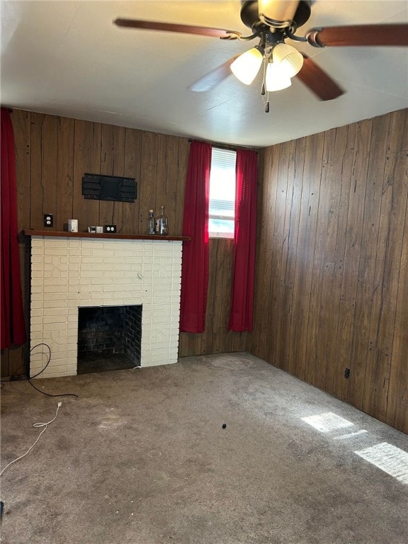 unfurnished living room with wooden walls, a fireplace, carpet, and ceiling fan