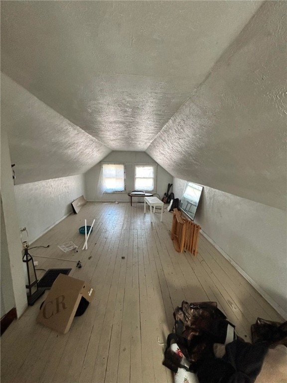 bonus room featuring light hardwood / wood-style floors, a textured ceiling, and vaulted ceiling