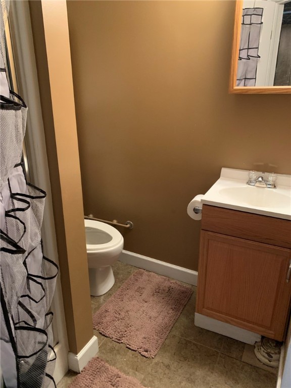 bathroom featuring toilet, tile flooring, and vanity