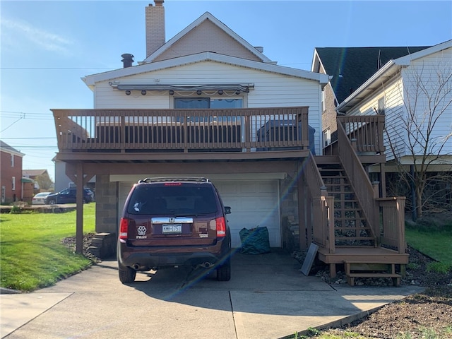 rear view of house featuring a yard, a garage, and a wooden deck