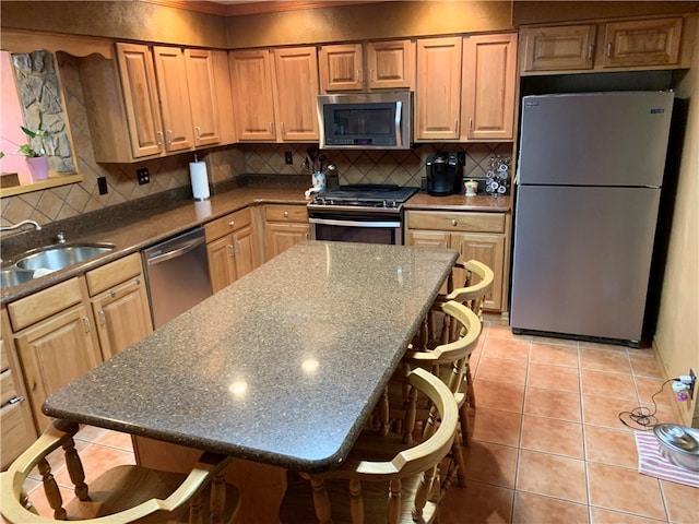 kitchen featuring a breakfast bar area, appliances with stainless steel finishes, light tile floors, and tasteful backsplash