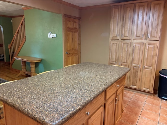 kitchen with light tile floors, a center island, and dark stone counters