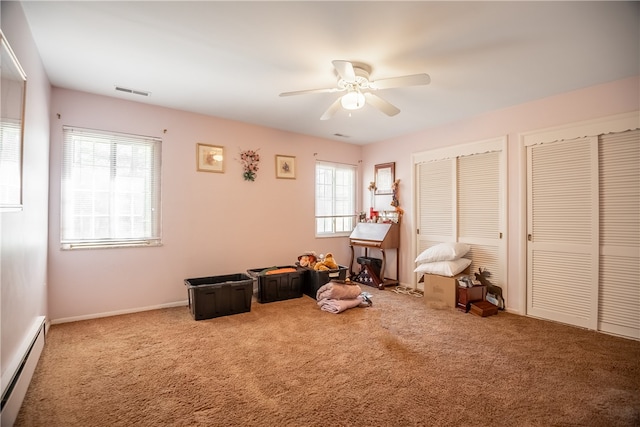 misc room featuring ceiling fan, carpet flooring, a wealth of natural light, and a baseboard heating unit