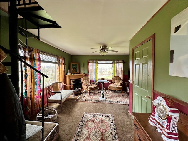 interior space featuring ceiling fan, a wealth of natural light, and dark colored carpet