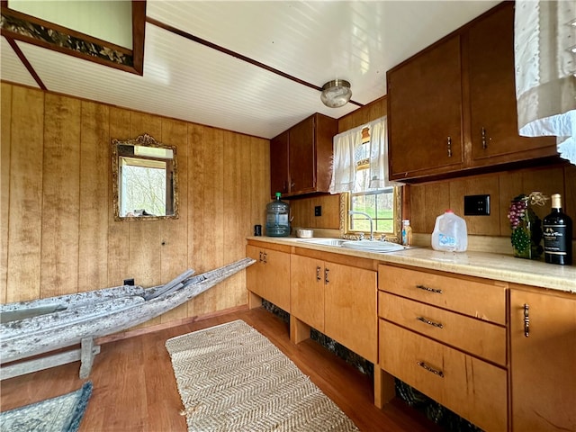 kitchen with wooden walls, sink, and hardwood / wood-style flooring