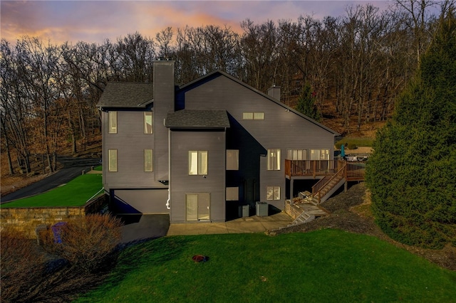 back house at dusk with a deck and a yard