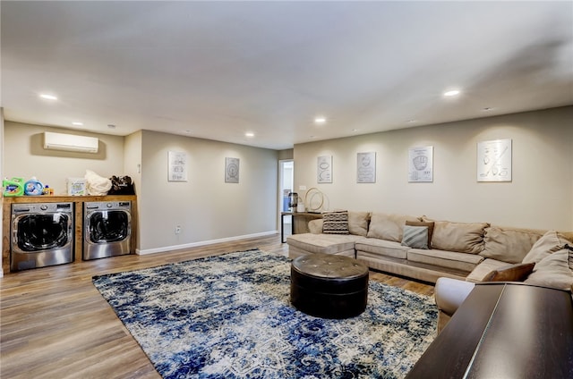 living room with washer and dryer, a wall mounted AC, and light hardwood / wood-style floors