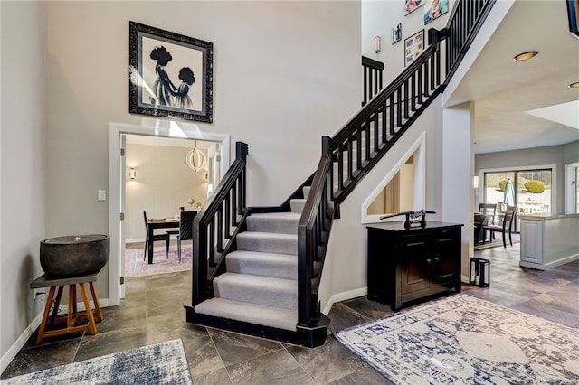 staircase with a chandelier and dark tile flooring