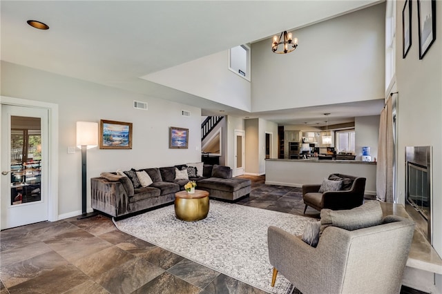 tiled living room featuring a high ceiling, a notable chandelier, and a healthy amount of sunlight