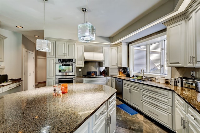 kitchen with decorative light fixtures, sink, stainless steel appliances, and dark stone countertops