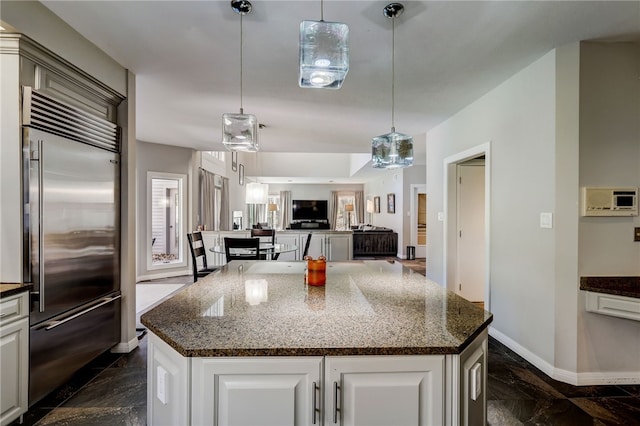 kitchen with stainless steel built in refrigerator, a kitchen island, pendant lighting, and white cabinets