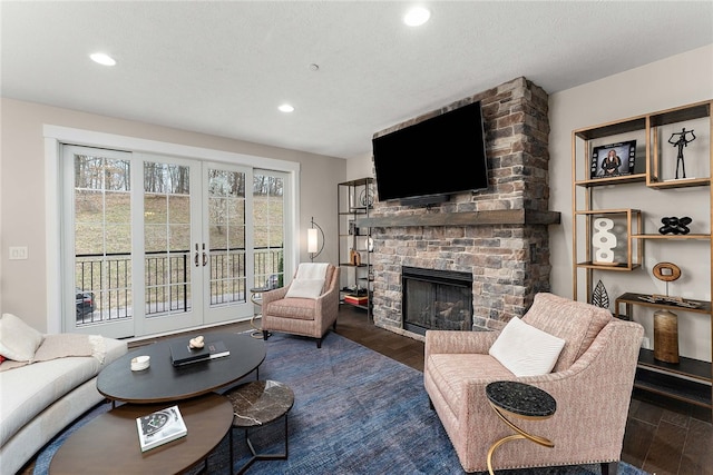 living room featuring a textured ceiling, french doors, a fireplace, and dark wood-type flooring