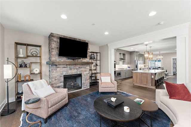 living room featuring dark hardwood / wood-style floors, a fireplace, a notable chandelier, and sink