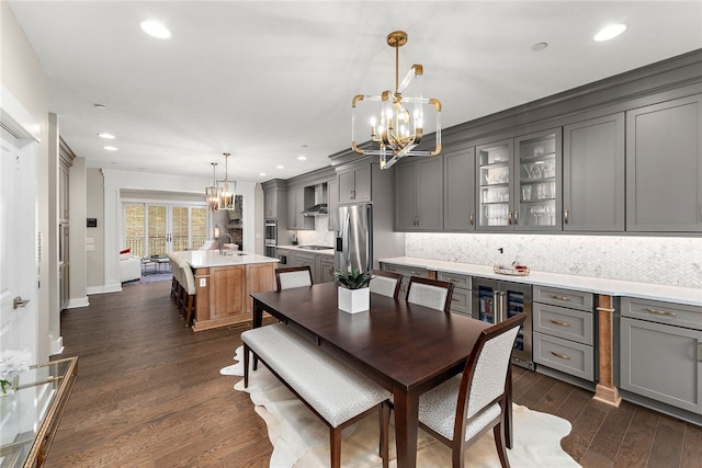 dining area featuring a chandelier, dark wood-type flooring, sink, and beverage cooler