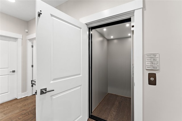 corridor with dark wood-type flooring and elevator