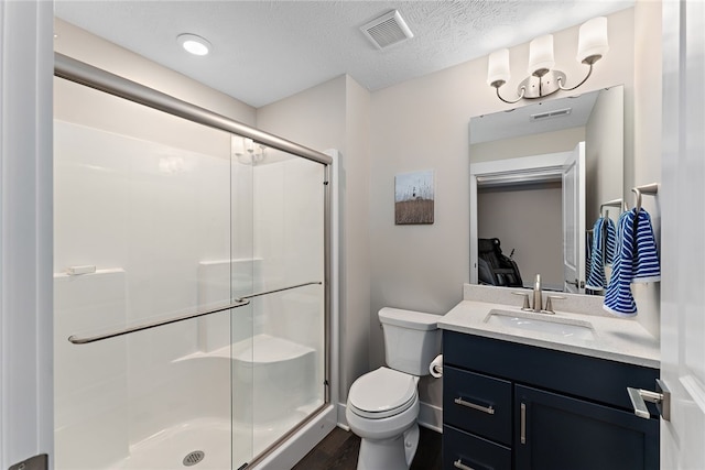 bathroom with vanity with extensive cabinet space, an enclosed shower, hardwood / wood-style flooring, toilet, and a textured ceiling