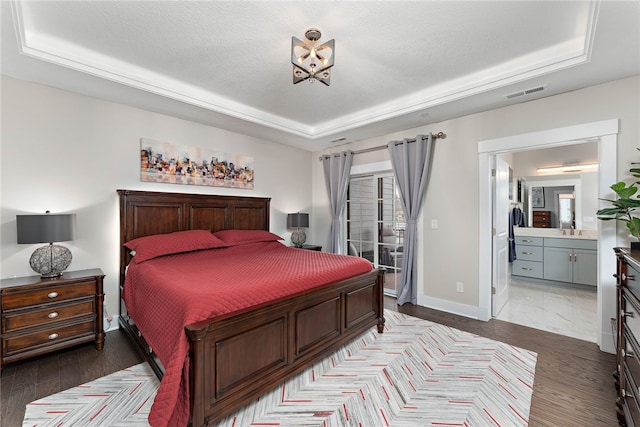 bedroom with ensuite bathroom, a textured ceiling, a tray ceiling, sink, and light tile floors