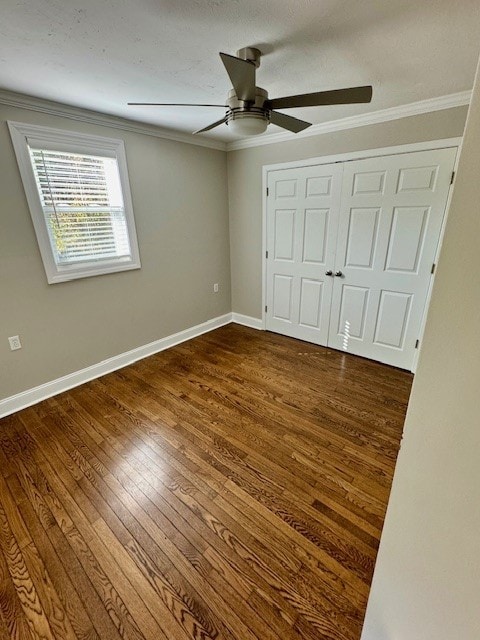 unfurnished bedroom with ornamental molding, dark wood-type flooring, ceiling fan, and a closet