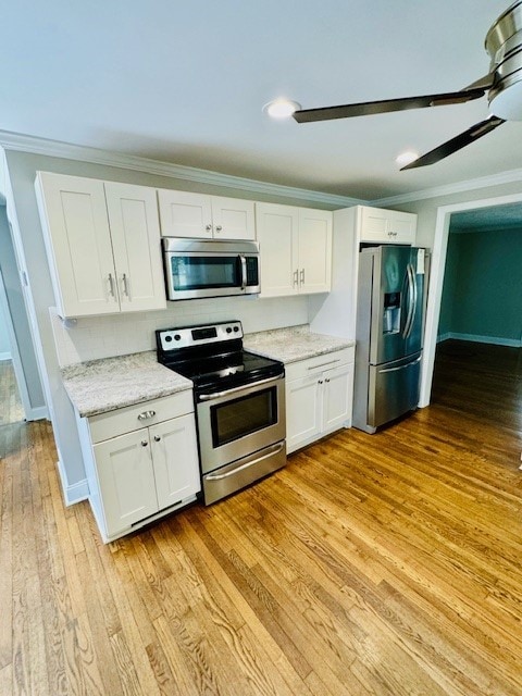 kitchen featuring appliances with stainless steel finishes, ornamental molding, light hardwood / wood-style flooring, and white cabinets