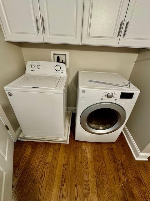 laundry room featuring separate washer and dryer, dark wood-type flooring, and cabinets