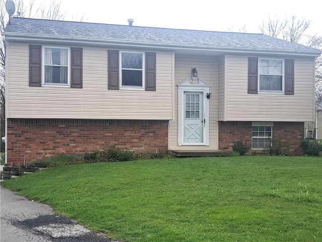 split foyer home with brick siding, a front lawn, and roof with shingles