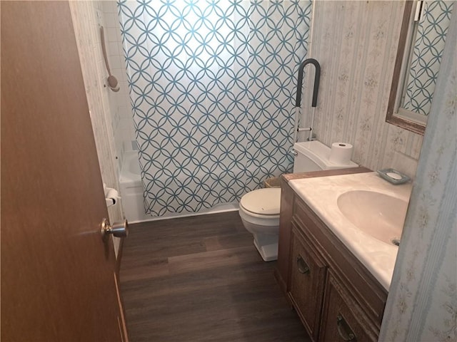 bathroom with wallpapered walls, toilet, wood finished floors, shower / bath combination with curtain, and vanity