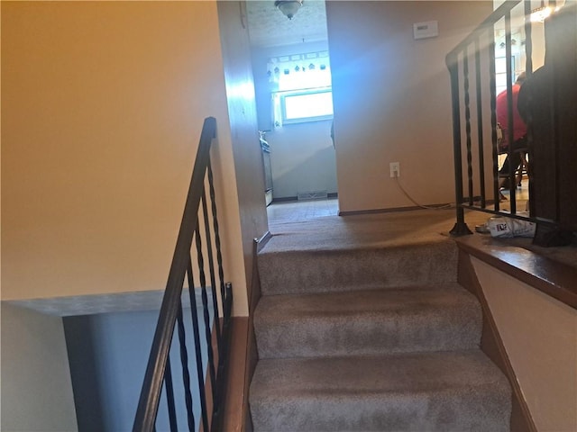 stairs with visible vents and carpet floors