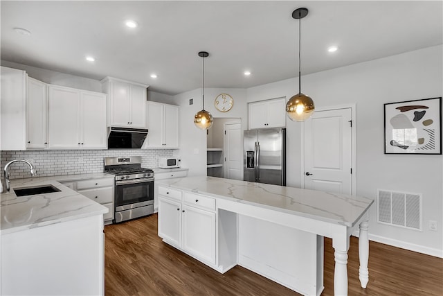 kitchen featuring appliances with stainless steel finishes, dark hardwood / wood-style floors, sink, and hanging light fixtures