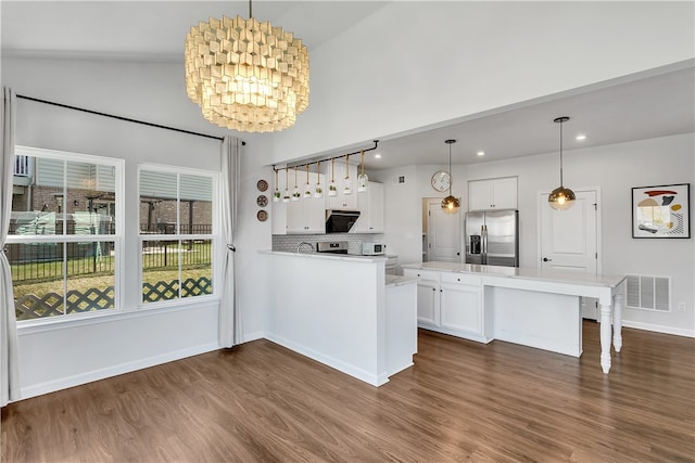 kitchen featuring white cabinetry, an inviting chandelier, stainless steel fridge, and lofted ceiling