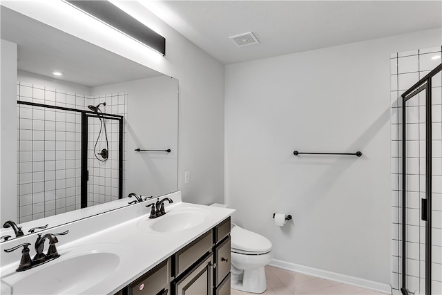 bathroom featuring vanity with extensive cabinet space, a shower with door, tile floors, dual sinks, and toilet