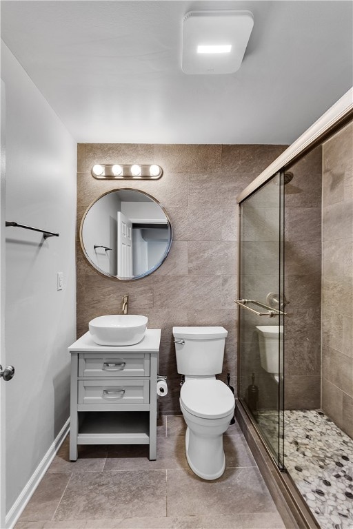 bathroom featuring tile flooring, tile walls, an enclosed shower, toilet, and vanity