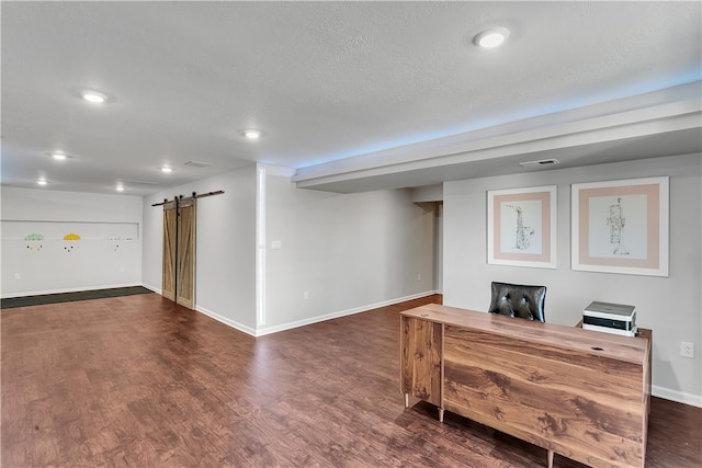 interior space with a textured ceiling, dark wood-type flooring, and a barn door