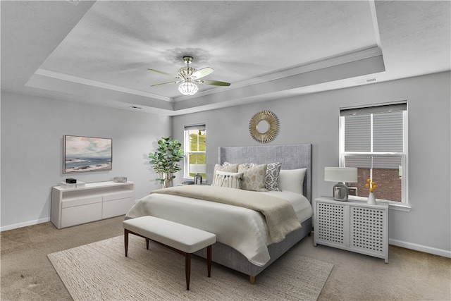 carpeted bedroom with ceiling fan and a tray ceiling