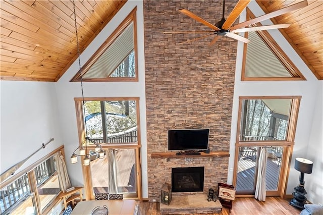 living room featuring ceiling fan, light hardwood / wood-style floors, high vaulted ceiling, and a fireplace