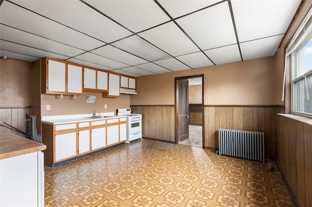 kitchen featuring radiator heating unit, a paneled ceiling, white range with gas cooktop, and white cabinets