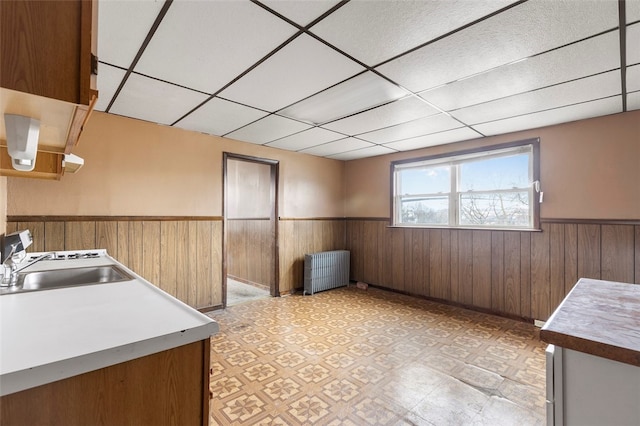 kitchen with light tile flooring, a drop ceiling, radiator, and sink